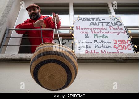 04 février 2021, Bade-Wurtemberg, Tübingen: Un restaurateur abaisse un panier de pâtes de son restaurant fermé. Avec l'« ascenseur des pâtes », le restaurant vend le déjeuner dans le confinement. (À dpa 'Corona Lockdown: L'opposition veut voir 'la lumière à la fin du tunnel') photo: Sebastian Gollnow/dpa Banque D'Images