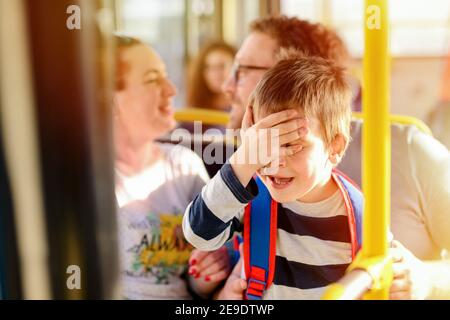 Mignon couple d'âge moyen assis dans un bus et baiser pendant que son fils est honteux. Banque D'Images