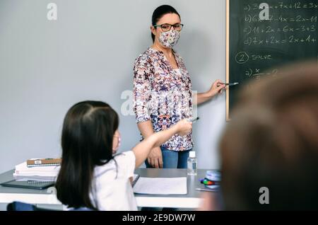 Professeur avec masque expliquant les exercices en cours de mathématiques Banque D'Images