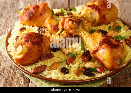 Riz épicé à l'arabe fait maison et poulet recouvert de noix, raisins secs dans l'assiette sur la table. Horizontal Banque D'Images