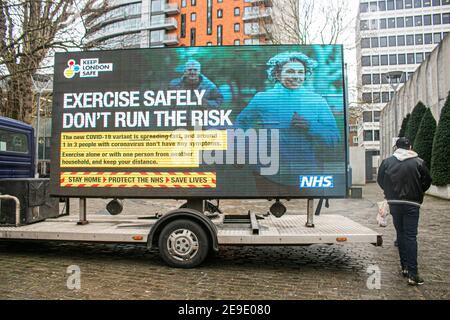 PUTNEY LONDRES, ROYAUME-UNI. 4 février 2021. Les gens marchent devant un grand panneau d'information digtial par le NHS England à Putney High Street dans le cadre de la campagne du gouvernement du NHS pour garder Londres en sécurité après la découverte d'une nouvelle variante sud-africaine Covid-19 sans lien avec l'Afrique du Sud dans huit codes postaux en Angleterre et dans le Sud Crédit est : amer ghazzal/Alamy Live News Banque D'Images