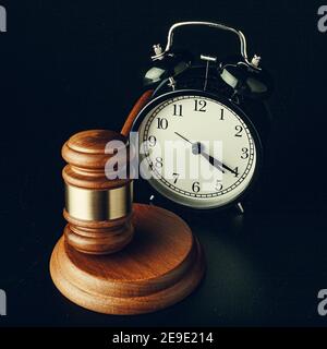 Marteau de juge en bois avec réveil sur fond noir Banque D'Images