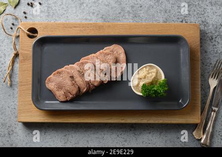 Émincé de langue de bœuf servant avec de la sauce au raifort sur bois et gris. Vue de dessus. Banque D'Images