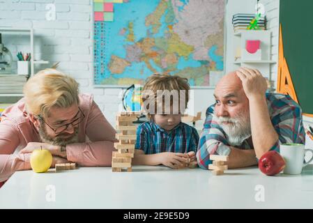 Mignon garçon heureux jouant avec son grand-père et son père assis dans une salle de classe. Banque D'Images