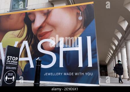 Un panneau d'affichage pour le détaillant de bijoux Vashi couvre leur extérieur de Covent Garden, derrière des panneaux exhortant les Londoniens à observer les règles de distance sociale de Covid pendant le troisième confinement de la pandémie du coronavirus, le 2 février 2021, à Londres, en Angleterre. Banque D'Images