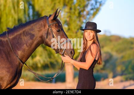 La fille se tient devant le cheval et tourne et regardé dans le cadre Banque D'Images