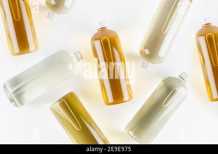 Recueillant les bouteilles transparentes avec différentes couleurs pâles liquide, produit cosmétique, parfum ou boisson et capuchon argenté sur fond blanc comme décoratif Banque D'Images