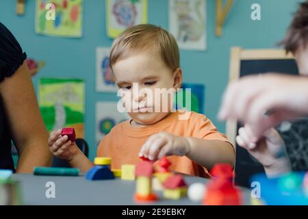 Un tout-petit concentré jouant avec des blocs et des formes d'apprentissage Banque D'Images