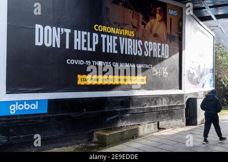 Un Londoner passe devant un panneau d'affichage du NHS (National Health Service) du gouvernement britannique - une annonce qui exhorte le public à aider à arrêter la propagation du virus pendant le troisième confinement de la pandémie du coronavirus, le 4 février 2021, dans le sud de Londres, en Angleterre. Banque D'Images