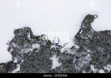 Aviemore, Écosse, Royaume-Uni. 4 février 2021. Le Loch VAA est complètement gelé et offre la possibilité de le traverser. Une petite tourbière est maintenant liée à la glace et trois dames du groupe de natation sauvage InVaa Dookers utilisent des haches pour briser la glace pour leur permettre de se tremper dans l'eau glacée pendant quelques minutes. Photo; vue aérienne du hangar à bateaux sur le Loch VAA gelé. Iain Masterton/Alay Live News Banque D'Images