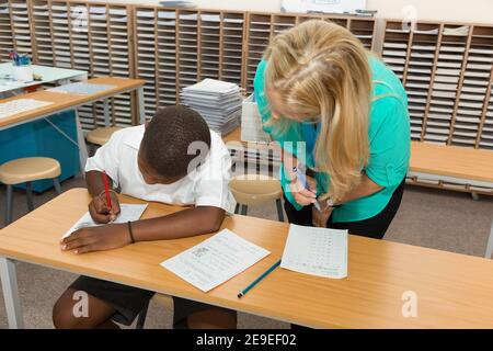 Johannesburg, Afrique du Sud - 11 février 2014 : un enseignant aide les jeunes garçons africains avec du matériel éducatif en classe Banque D'Images