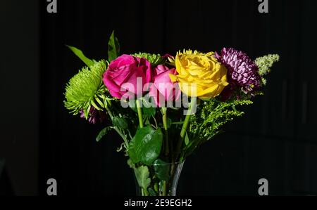 Bouquet de fleurs de Saint-Valentin avec roses jaunes équatoriennes et fuchsia et chrysanthèmes à fond noir. Banque D'Images