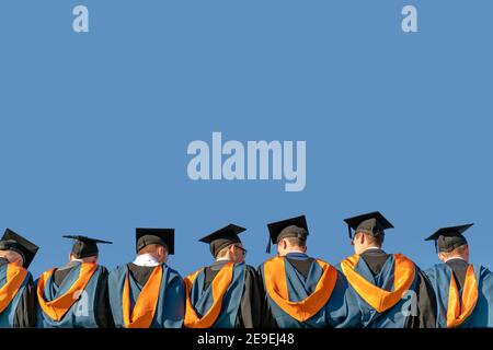 Une ligne de diplômés, vêtus de robes et de planches à mortier, attendent en file lors de leur cérémonie de remise des diplômes. Banque D'Images