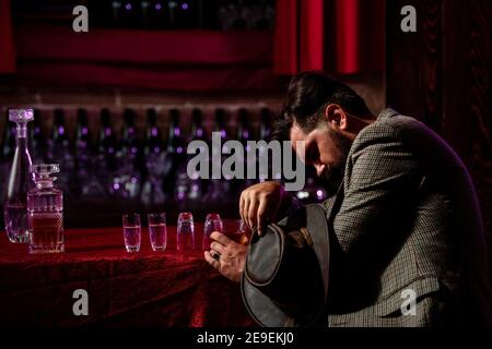 Alcoolisme, dépendance à l'alcool et concept de personnes - homme alcoolique avec un verre de whisky et une bouteille couchée ou dormant sur table à la boîte de nuit. Banque D'Images