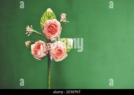 Souche artificielle avec trois roses sur fond vert. Copier l'espace, vue avant Banque D'Images