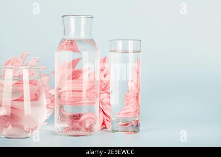 fleurs roses déformées par l'eau dans les verres et la bouteille sur fond bleu. Décoration maison, écologique, détente, concept de jardinage. Espace copie Banque D'Images