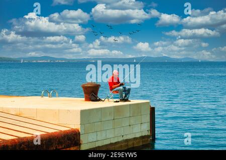 Homme pêche hors port, vieille ville, Zadar, côte dalmate. Mer Adriatique, Croatie Banque D'Images