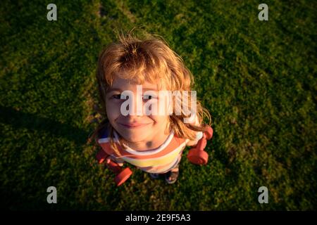 Visage d'enfant drôle. Enfant avec haltères. Grand angle. Entraînement sportif et santé des personnes. Banque D'Images