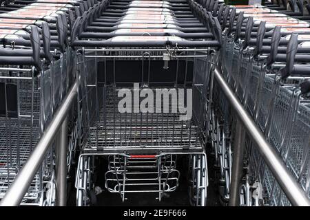 Les rangées de chariots de supermarché sont garées entre l'acier inoxydable tuyaux par temps de pluie Banque D'Images