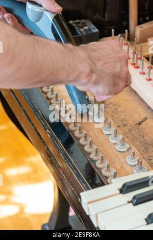 Installation d'un vieux piano. Le maître répare un vieux piano. Nettoyage en profondeur du piano. Mains d'un professionnel réparant et réglant un vieux piano Banque D'Images