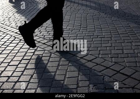 Détail des personnes qui se précipitent sur le trottoir à un train station pendant les heures de pointe avec le soleil venant du côté et de longues ombres Banque D'Images