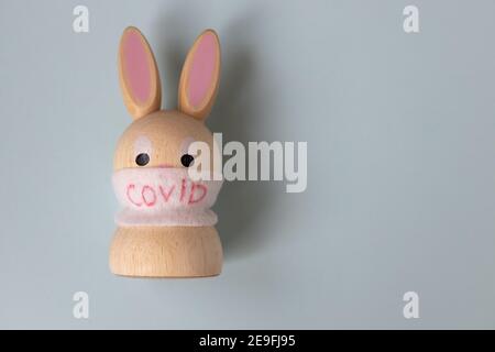 Jouet lapin en bois de Pâques dans un masque médical avec l'inscription COVID sur fond gris. Concept pour la santé, la médecine, la science, les vacances pendant le quar Banque D'Images