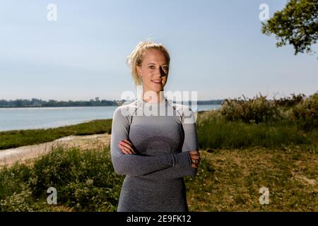 Belle tenue jeune femme en sport prêt à l'entraînement au soleil sur la rive de la rivière. Concept de mode de vie sain Banque D'Images