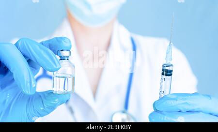 Une femme médecin tient dans ses mains une petite bouteille transparente avec un médicament et une seringue avec une aiguille. Vaccination de routine et vaccination du Banque D'Images