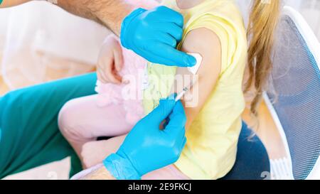 Vaccination et vaccination des enfants. Un médecin de sexe masculin donne un vaccin à une fille avec son jouet en peluche. Vaccination des enfants contre le coronavir COVID-19 Banque D'Images