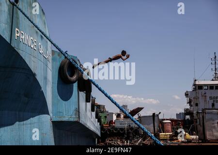 Un enfant plonge depuis un bateau amarré près de l'enceinte du Baseco à Manille comme des plates-formes de plongée improvisées pendant qu'il se rafraîchie dans la baie de Manille vendredi. Philippines. Banque D'Images