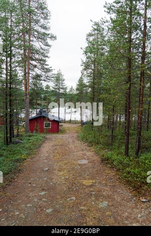 Chemin mène à la belle idyllique cottage en bois rouge dans la nature d'arrivée. Chalet isolé à Inari, Laponie, Finlande pour des vacances romantiques Banque D'Images