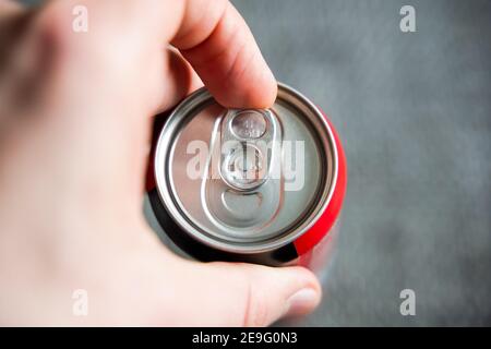 Tirer la languette d'une boîte à boissons avec une main mâle gauche. Ouverture d'une boisson rafraîchissante comme le cola ou l'énergisant après une dure journée Banque D'Images