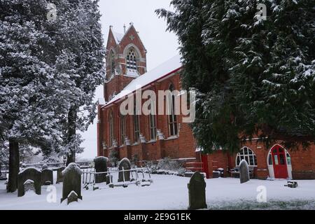 Une église victorienne rurale et un chantier de curriérie en Angleterre couvert en neige Banque D'Images