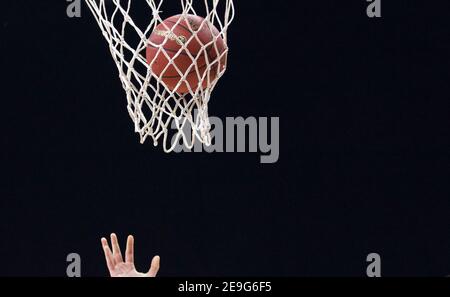 Filet de basket-ball gros plan avec ballon et fond noir. Banque D'Images