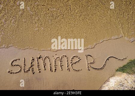 Été écrit sur le sable de mer. Fond de sable naturel avec plage et vague pure transparente. Placer pour le texte Banque D'Images