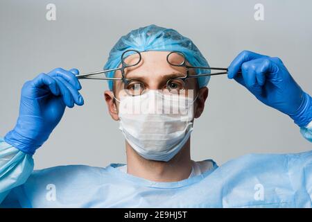 Un médecin chirurgien souriant et enragnant avec des émotions folles. Jeune médecin tenant des ciseaux médicaux Banque D'Images