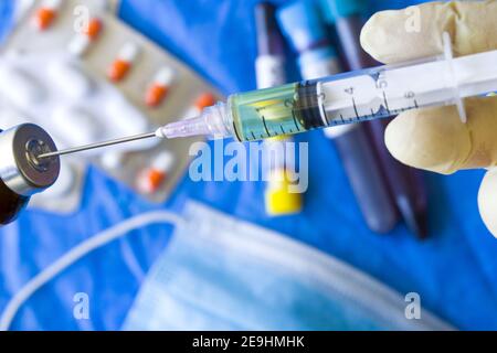 Mise au point sélective d'une main dans des gants en sortant le liquide provenant d'un flacon avec une seringue Banque D'Images