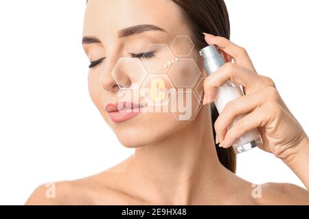 Femme appliquant du sérum cosmétique avec de la vitamine C sur son visage sur fond blanc Banque D'Images