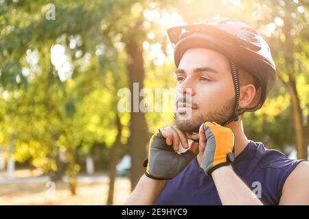 Cycliste masculin mettant le casque à l'extérieur Banque D'Images