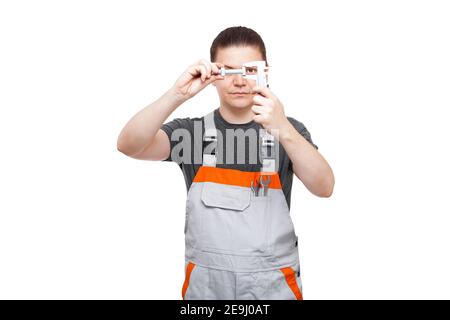 le mécanicien mâle en uniforme maintient le boulon et le pied à coulisse en place la poche avec clé à ergots permet de contrôler la mesure de la taille de pièce en acier avec th Banque D'Images