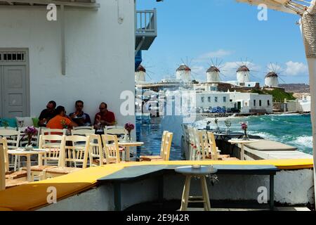 Mykonos, Grèce personnes assises et dînant dans des bars et des restaurants le long du front de mer de la petite Venise dans la vieille ville de Mykonos avec des moulins à vent dans le dist Banque D'Images