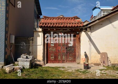 Porte traditionnelle de style ancien et entrée d'une maison à Shangri la , Yunnan, Chine. Tuiles de toit en céramique rouge brique vues dans toute la ville. Banque D'Images