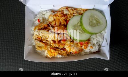 Hache de poulet Ayam geprek ou Spicy avec saveur de piment et d'ail sur plaque blanche isolée sur fond blanc. Cuisine indonésienne épicée. Banque D'Images