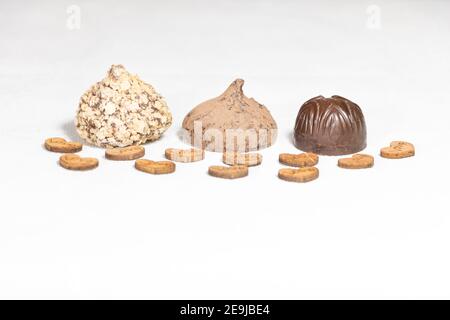 Trois sortes de chocolat sur fond blanc - et quelques coeurs en bois. Banque D'Images