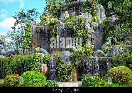 Pattaya, Chonburi / Thaïlande - 08/08/2020: Un jardin avec une cascade murale et des arbres avec des statues d'un serpent mythique et des fées thaïlandaises à Suanthai. Banque D'Images