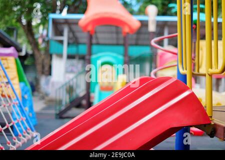 Une photo en gros plan d'un toboggan rouge sur un terrain de jeu dans un parc public. Banque D'Images