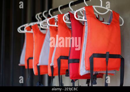 Une rangée de gilet de sauvetage orange ou une veste accrochée sur un rack, se préparer à être utilisé par les touristes se rendant sur un voyage en bateau. Banque D'Images