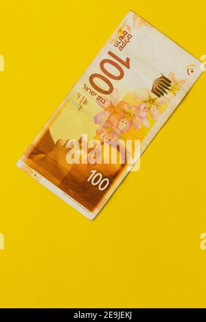 Un nouveau billet de banque israélien d'une centaine de shekels, fond jaune Banque D'Images