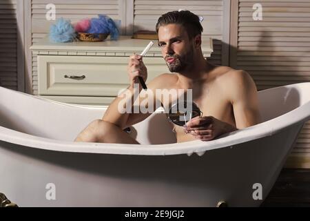 Homme rasoir droit. Le modèle masculin se rassera avec soin et en douceur avec un rasoir ancien. Gars dans la salle de bains Banque D'Images