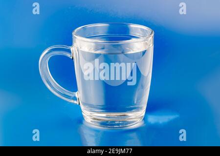 gobelet en verre avec manche à eau transparent sur fond bleu Banque D'Images